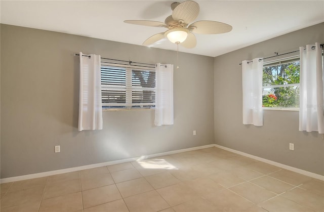 spare room with light tile patterned floors, a ceiling fan, and baseboards