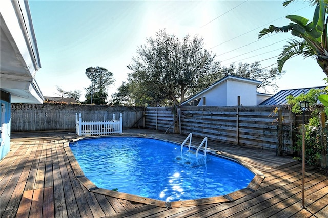 view of pool featuring a fenced in pool, a fenced backyard, and a wooden deck