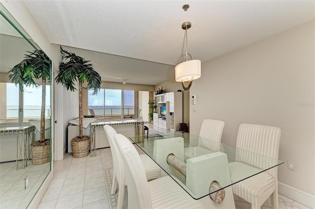 tiled dining room featuring a water view and a textured ceiling