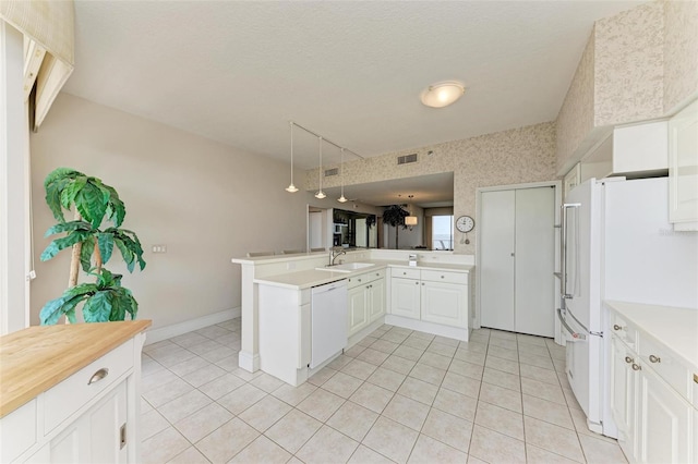 kitchen featuring sink, white cabinets, kitchen peninsula, white appliances, and light tile patterned floors