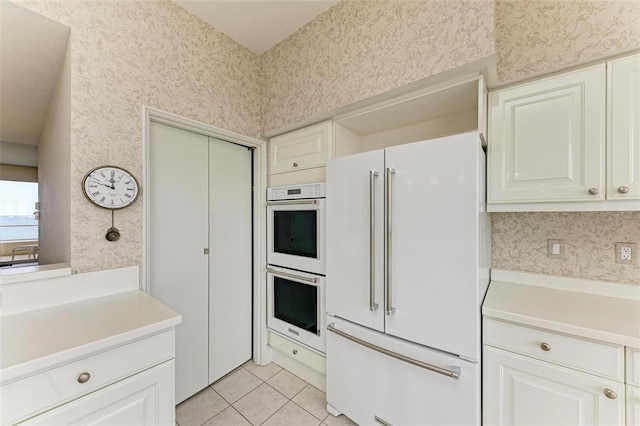 kitchen with white cabinets, white appliances, and light tile patterned flooring