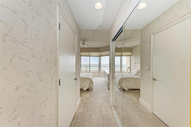 bedroom featuring ceiling fan, a water view, and light carpet