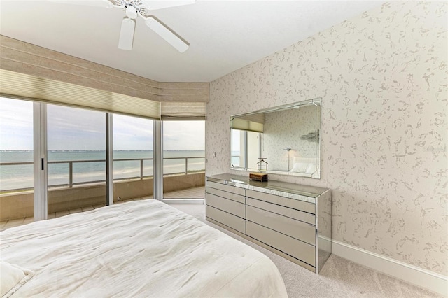 carpeted bedroom featuring access to outside, a water view, and ceiling fan