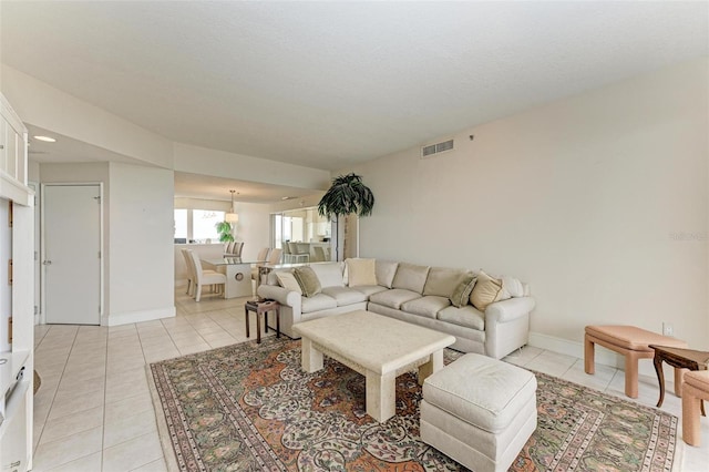 living room featuring light tile patterned flooring, visible vents, and baseboards