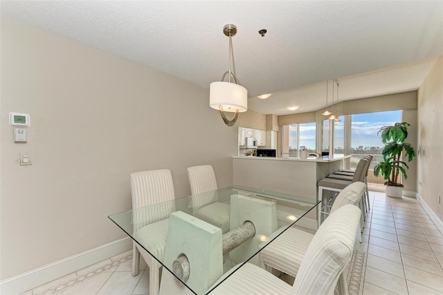 dining space with a textured ceiling, baseboards, and light tile patterned floors