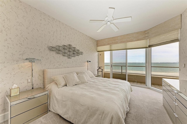 bedroom featuring a water view, a ceiling fan, light carpet, access to outside, and wallpapered walls