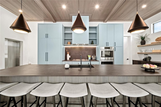 kitchen with blue cabinetry, pendant lighting, beam ceiling, and sink