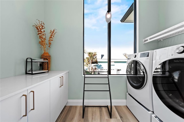 laundry room featuring washer and clothes dryer, cabinets, and light wood-type flooring