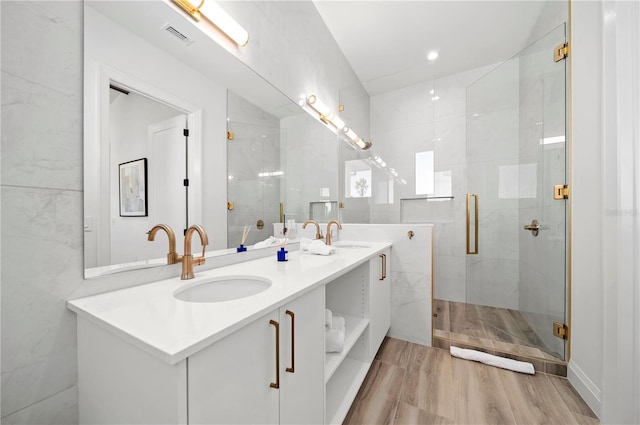 bathroom with hardwood / wood-style floors, vanity, a shower with shower door, and tile walls