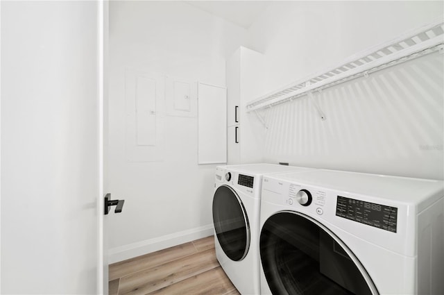 laundry area featuring light hardwood / wood-style floors, separate washer and dryer, and electric panel