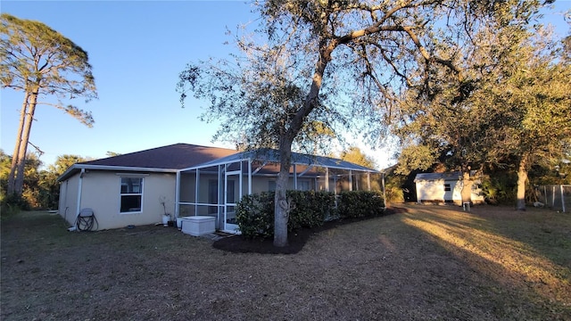 back of property featuring a lawn and a storage shed