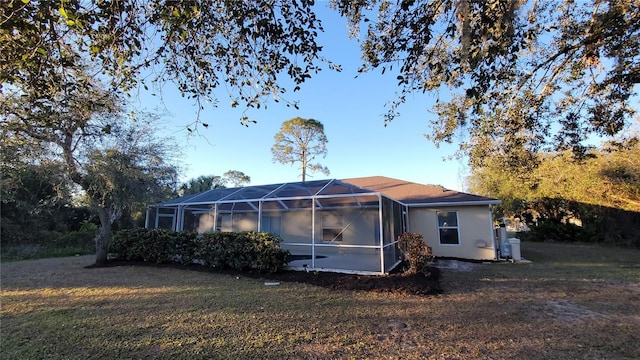 back of property featuring glass enclosure and a yard