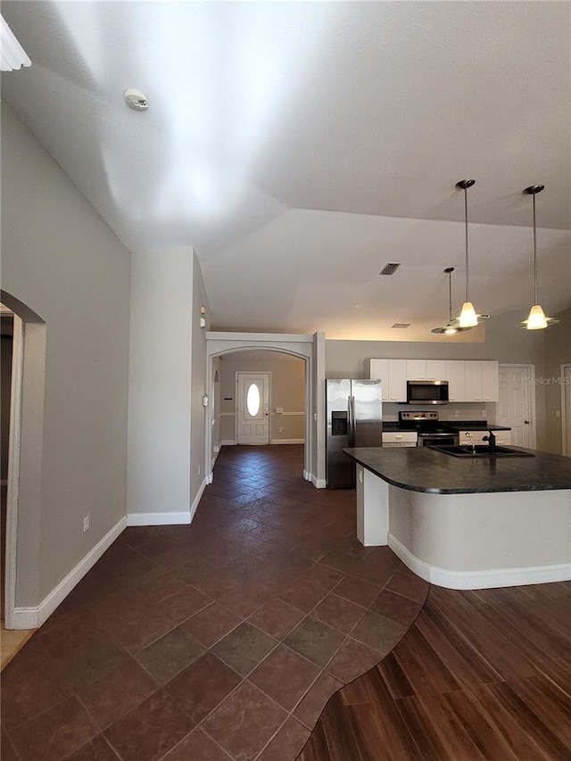 kitchen with white cabinetry, sink, hanging light fixtures, vaulted ceiling, and appliances with stainless steel finishes