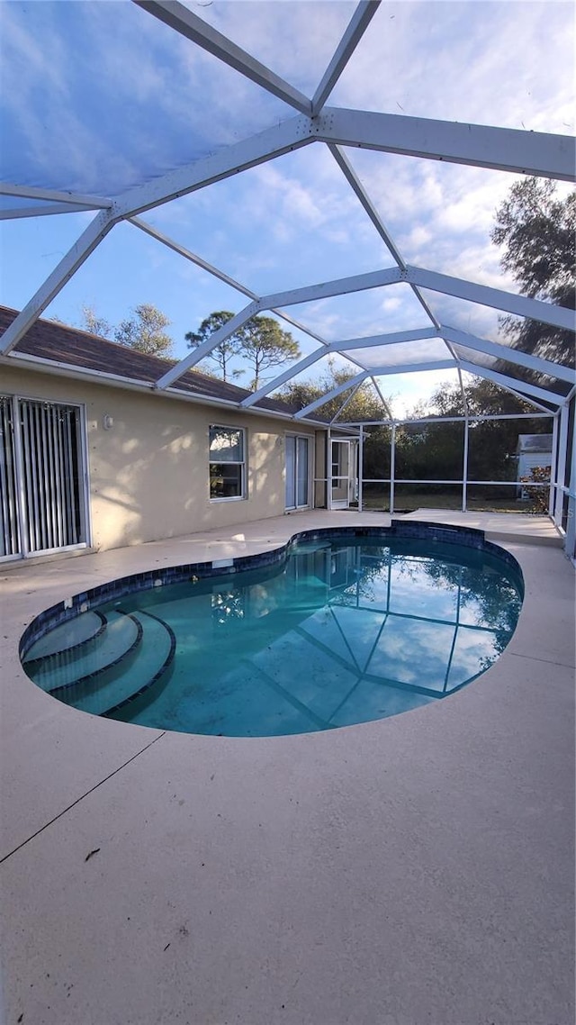 view of swimming pool with glass enclosure and a patio area