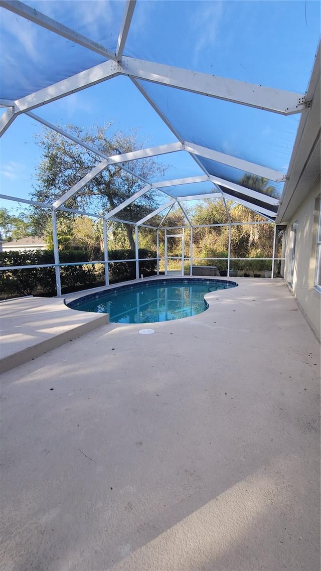 view of pool featuring glass enclosure and a patio area