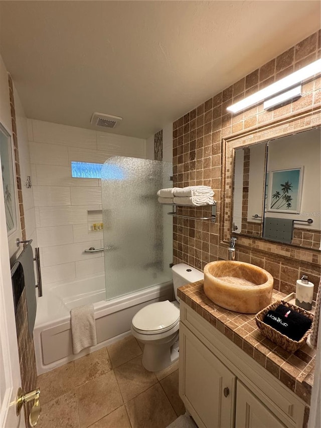 full bathroom with tile patterned flooring, backsplash, toilet, vanity, and tiled shower / bath