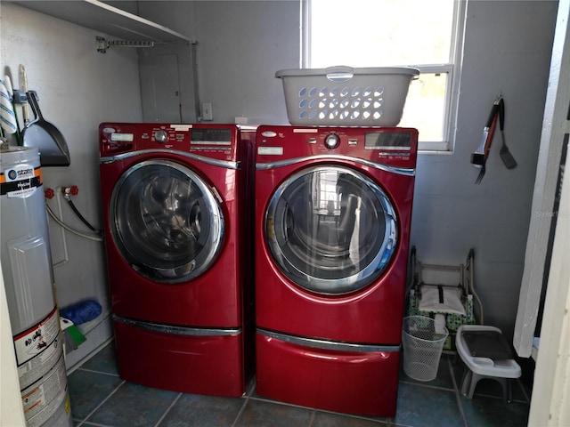 clothes washing area featuring washing machine and clothes dryer, electric water heater, and dark tile patterned floors