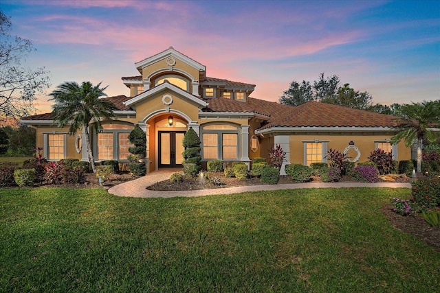 mediterranean / spanish home with a lawn and french doors