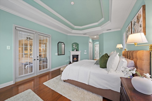 bedroom featuring dark hardwood / wood-style floors, a raised ceiling, crown molding, and access to outside