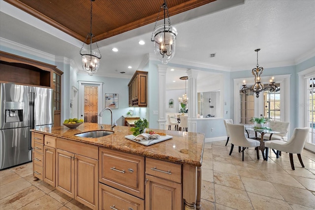 kitchen with stainless steel fridge, a center island with sink, hanging light fixtures, and sink