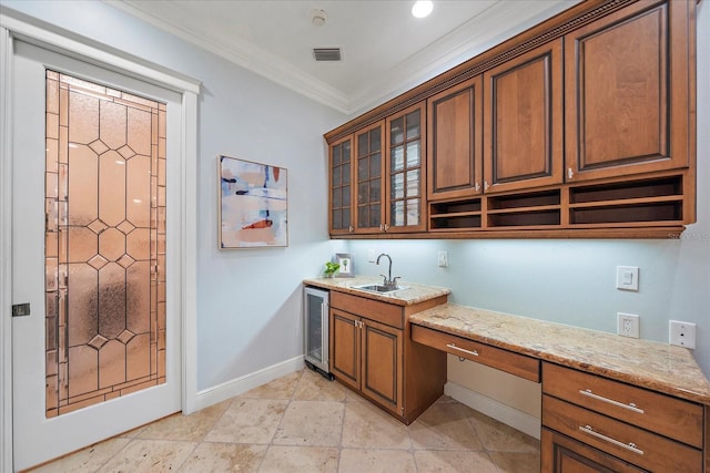 kitchen with sink, wine cooler, light stone countertops, built in desk, and ornamental molding