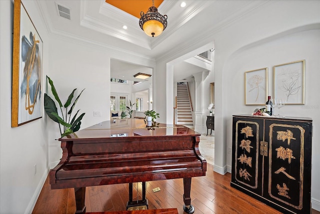 misc room featuring wood-type flooring, crown molding, and a tray ceiling