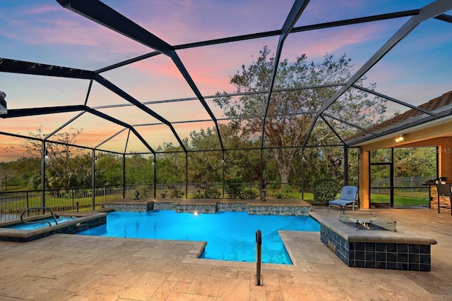 pool at dusk with glass enclosure, a patio area, and an in ground hot tub