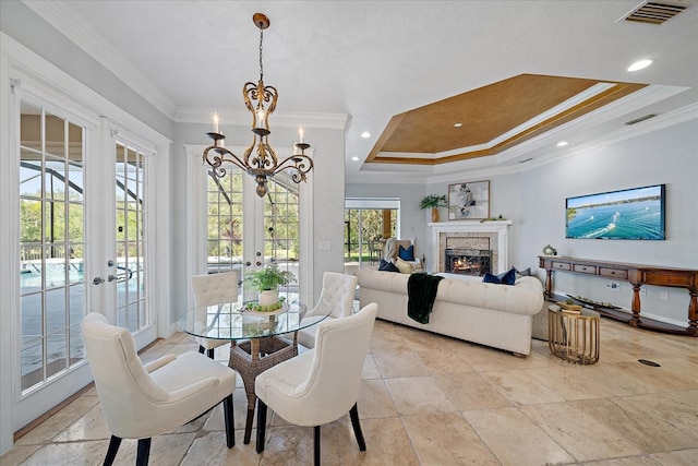 dining room with french doors, an inviting chandelier, a raised ceiling, and ornamental molding