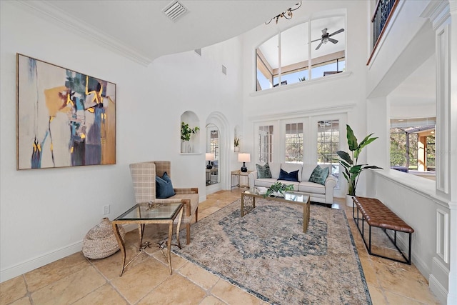 living room with ceiling fan, ornamental molding, and a high ceiling