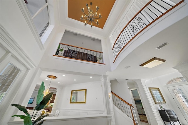 entrance foyer with ornamental molding, a high ceiling, and a chandelier