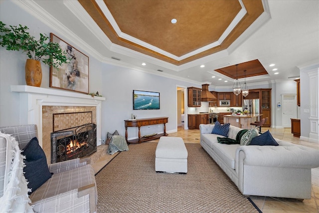 living room featuring a fireplace, light tile patterned floors, a tray ceiling, and ornamental molding