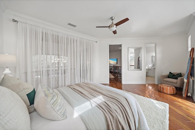 bedroom with hardwood / wood-style flooring, ceiling fan, crown molding, and ensuite bath