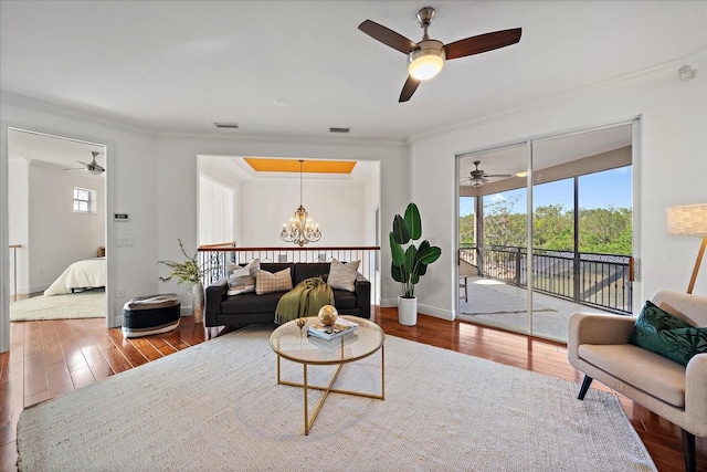 living room featuring hardwood / wood-style floors, ceiling fan with notable chandelier, and crown molding