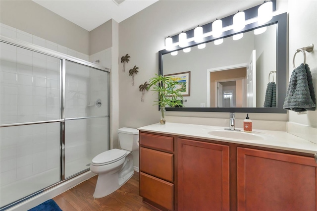 bathroom featuring toilet, vanity, a shower with shower door, and hardwood / wood-style flooring