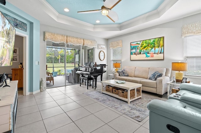 tiled living room featuring a tray ceiling, ceiling fan, and crown molding