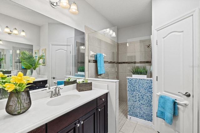 bathroom featuring tile patterned flooring, vanity, and a tile shower