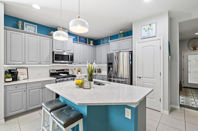 3922 Wildgrass Pl, Parrish, FL 34219 - kitchen featuring appliances with stainless steel finishes, light tile patterned flooring, light countertops, decorative light fixtures, and an island with sink