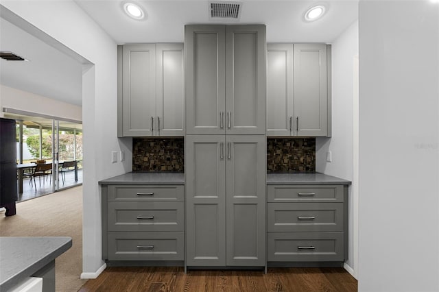 bar featuring gray cabinets, decorative backsplash, and dark carpet