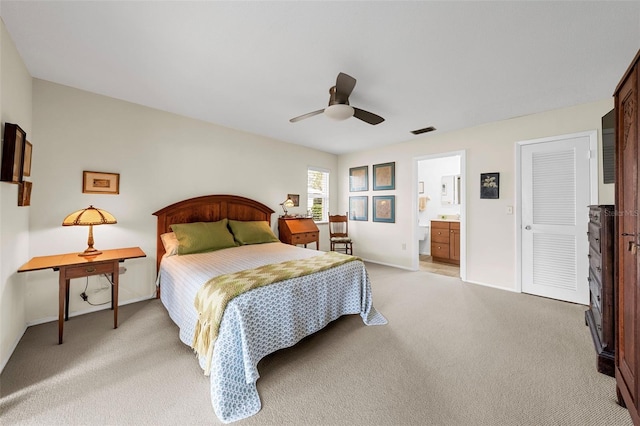 carpeted bedroom featuring a closet, ensuite bathroom, and ceiling fan