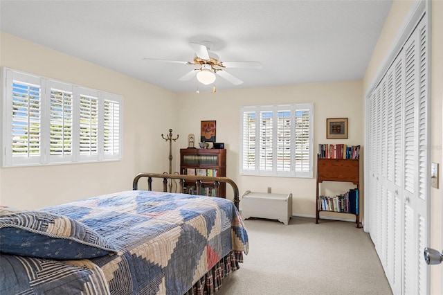 bedroom with ceiling fan, light colored carpet, and a closet