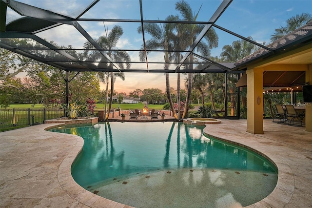 view of pool featuring glass enclosure, an in ground hot tub, a fire pit, and a patio