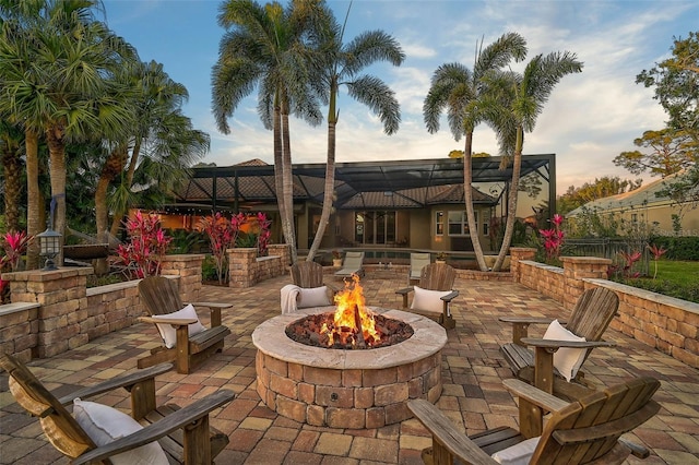 patio terrace at dusk with glass enclosure and an outdoor fire pit