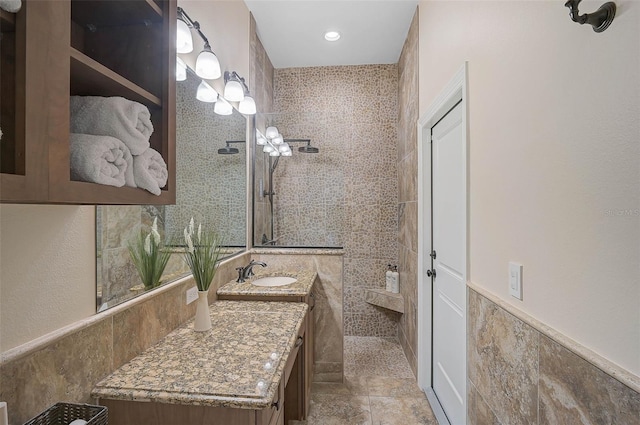 bathroom featuring tile walls, tiled shower, and vanity