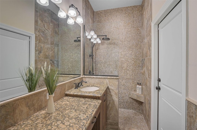 bathroom featuring tile walls, vanity, and a tile shower