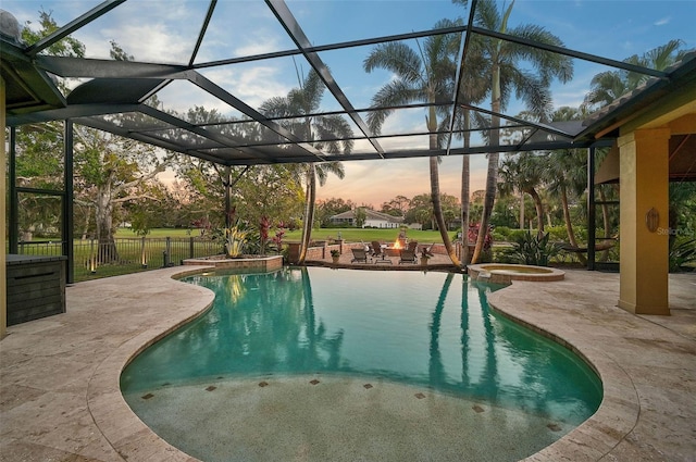 pool at dusk featuring a lanai, a fire pit, a patio, and an in ground hot tub