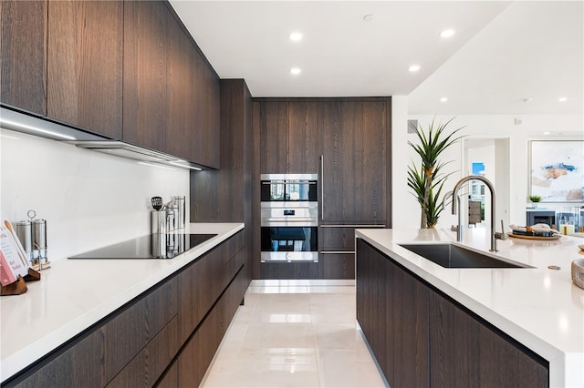 kitchen featuring sink, dark brown cabinets, light tile patterned floors, double oven, and black electric stovetop