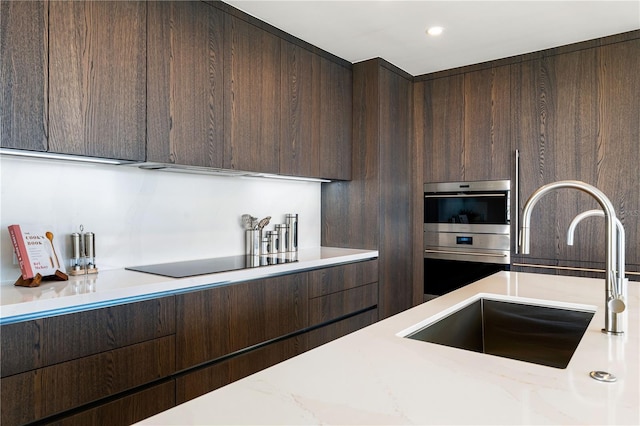 kitchen featuring dark brown cabinets, sink, black electric stovetop, and light stone counters