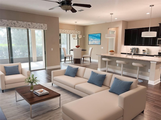 living room featuring hardwood / wood-style floors, ceiling fan, and sink