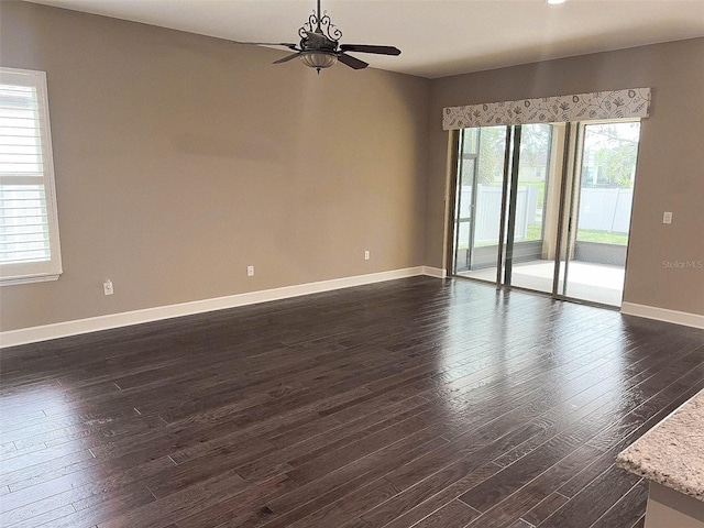 empty room featuring dark hardwood / wood-style flooring, a wealth of natural light, and ceiling fan