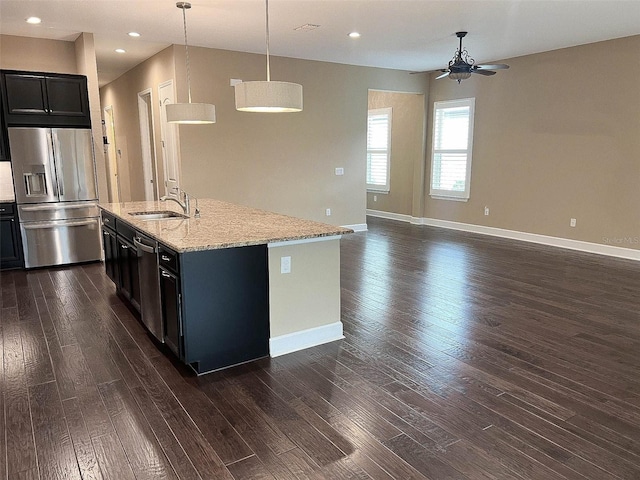 kitchen with ceiling fan, sink, stainless steel appliances, pendant lighting, and a center island with sink